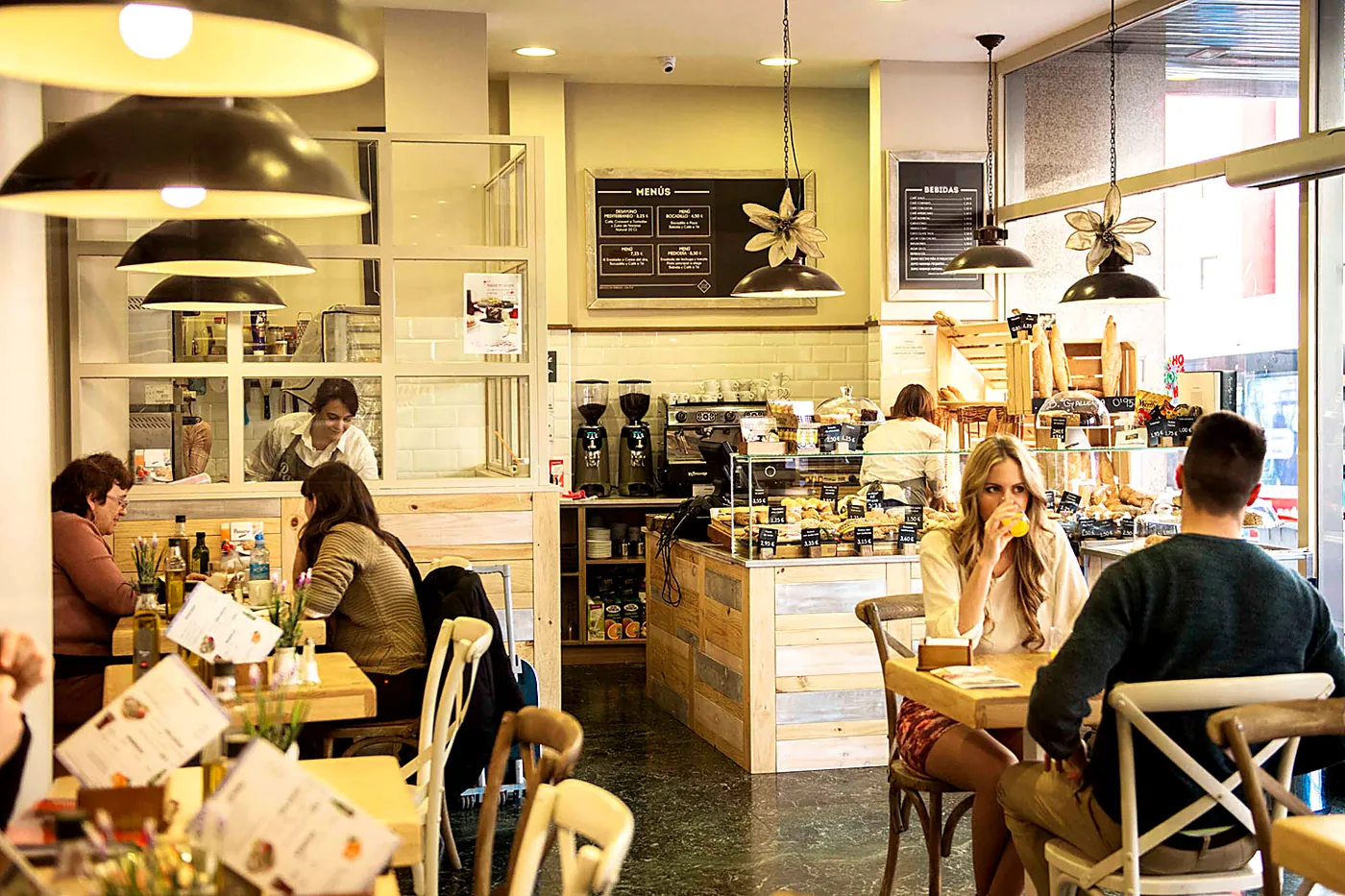 Ricitos Café con clientes desayunando, mostrador de madera y lámparas colgantes