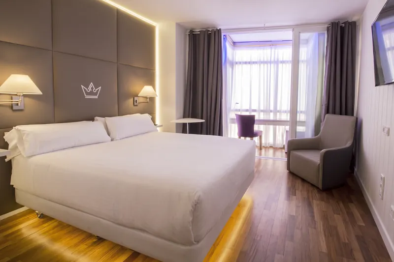 Habitación doble con cama grande, butaca y ventanal